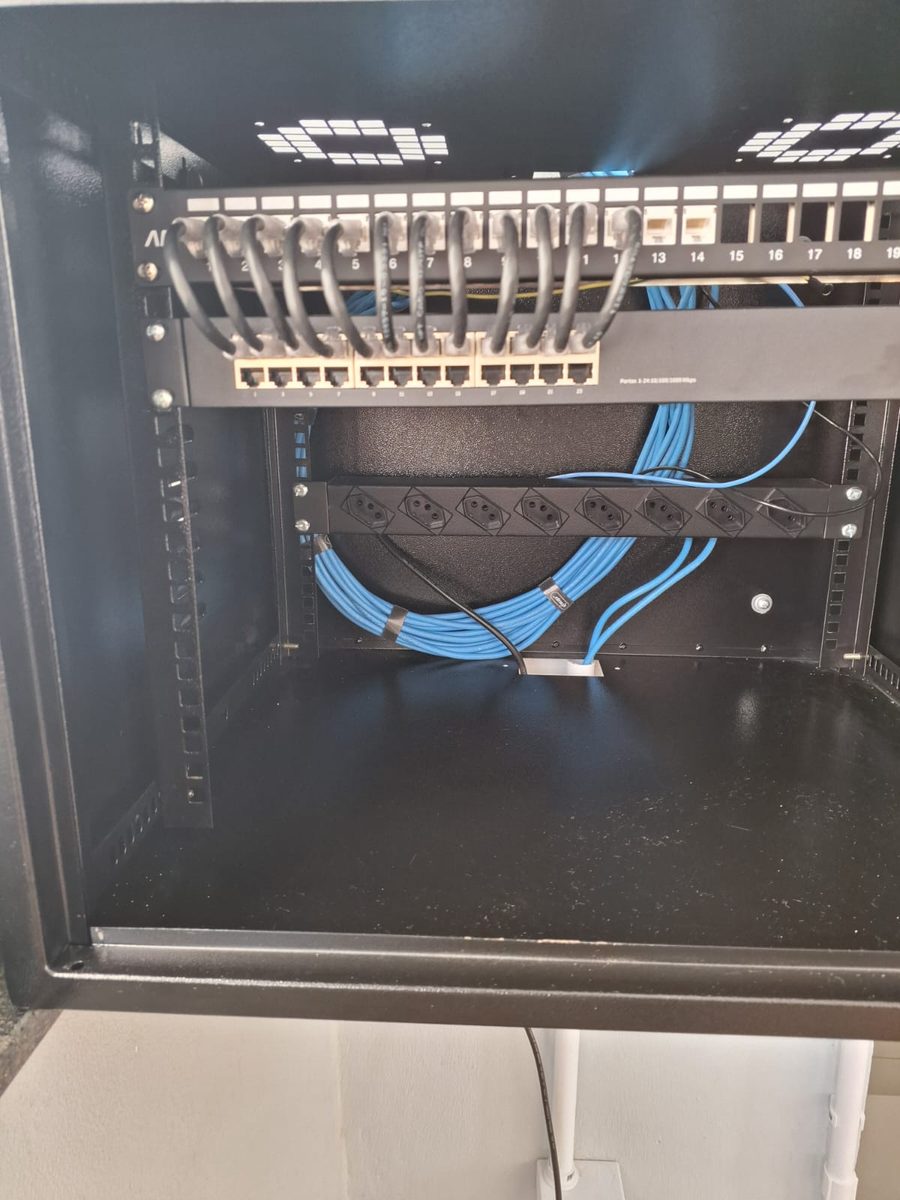 Patch panel com cabeamento organizado e régua de energia no rack